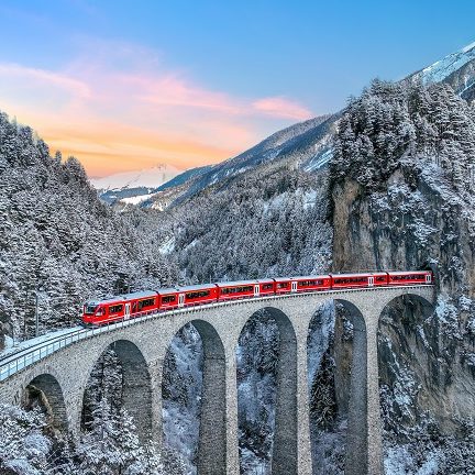 Vue aérienne d'un train rouge traversant le célèbre viaduc de Landwasser à Filisur, en Suisse, classé au patrimoine mondial de l'UNESCO.
