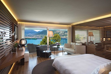 Hôtel Lugano Chambre moderne avec vue sur un lac et des montagnes, décor épuré et lumineux.