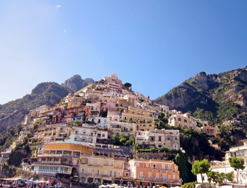 Vue de Positano avec des maisons colorées sur la colline et un ciel bleu.