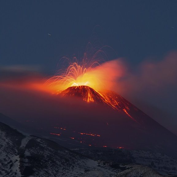 Éruption volcanique de l'Etna en Sicile, Italie, au crépuscule, avec des jets de lave illuminant le ciel.